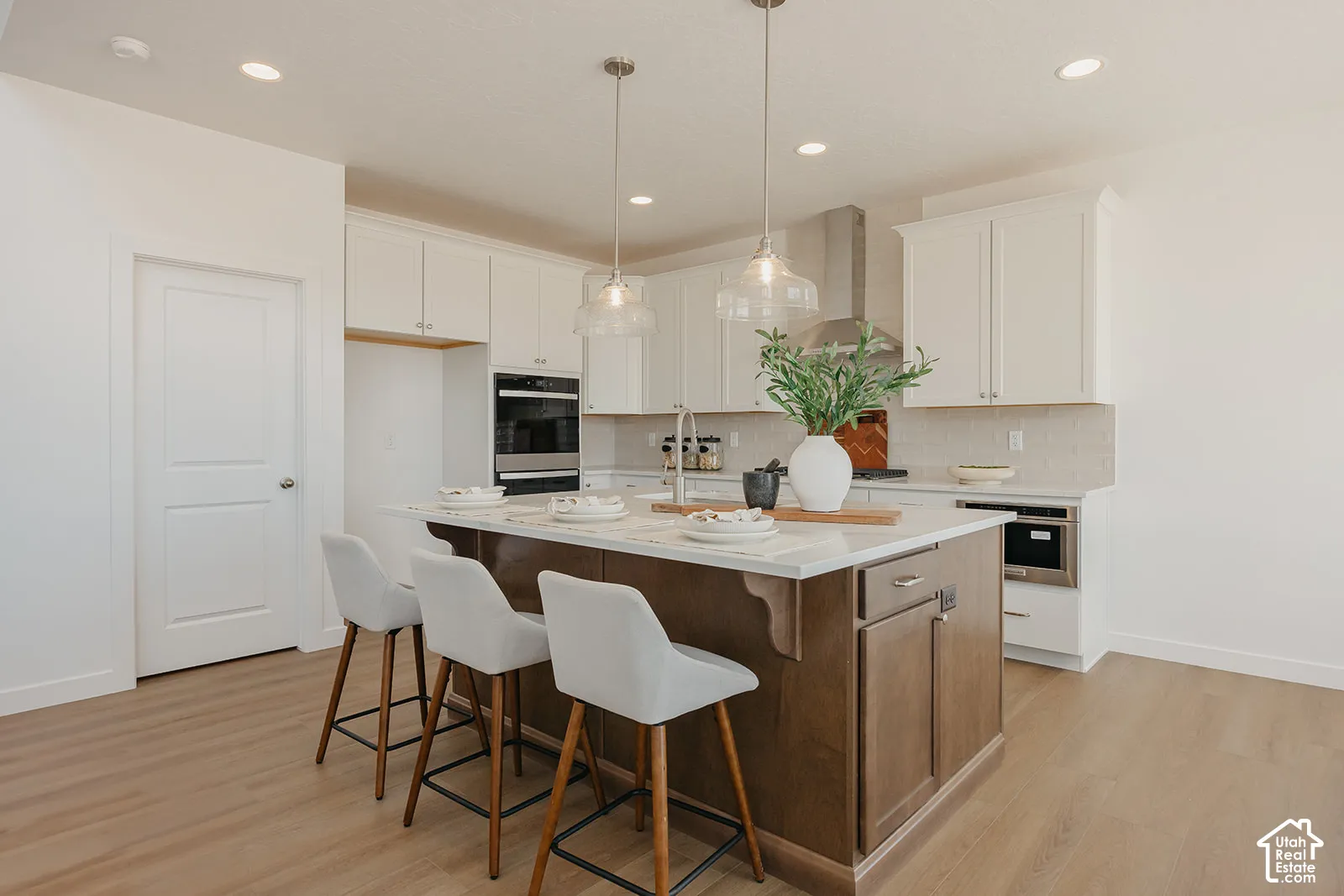 Kitchen featuring white cabinetry, wood-finish flooring, a central island with a stone countertop, recessed lighting, and stainless steel built-in appliances