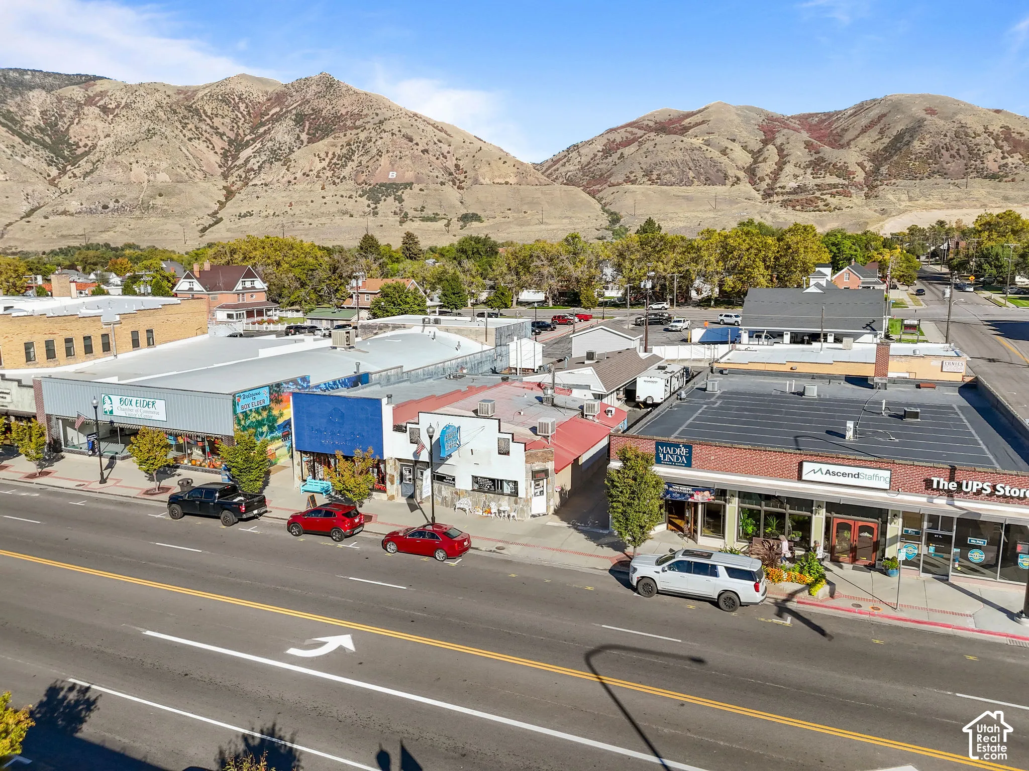 Commercial streetscape featuring brick and stucco storefronts with prominent mountain backdrop