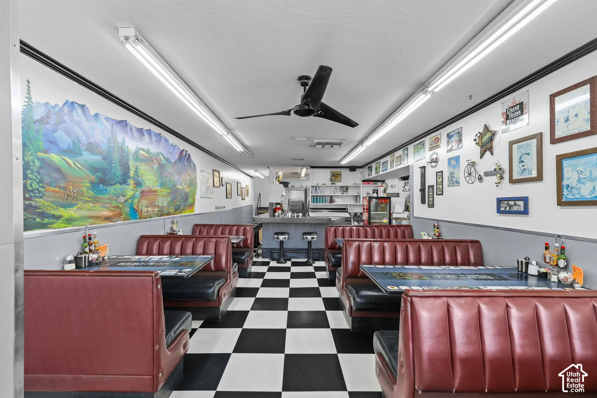 Commercial space featuring  built-in booth seating, integrated service counter, wall-mounted ceiling fan, and fluorescent track lighting