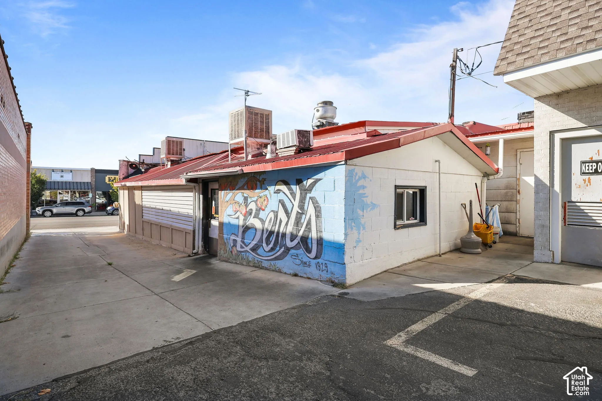 Concrete block exterior with a metal roof, rooftop HVAC units, and paved asphalt surface