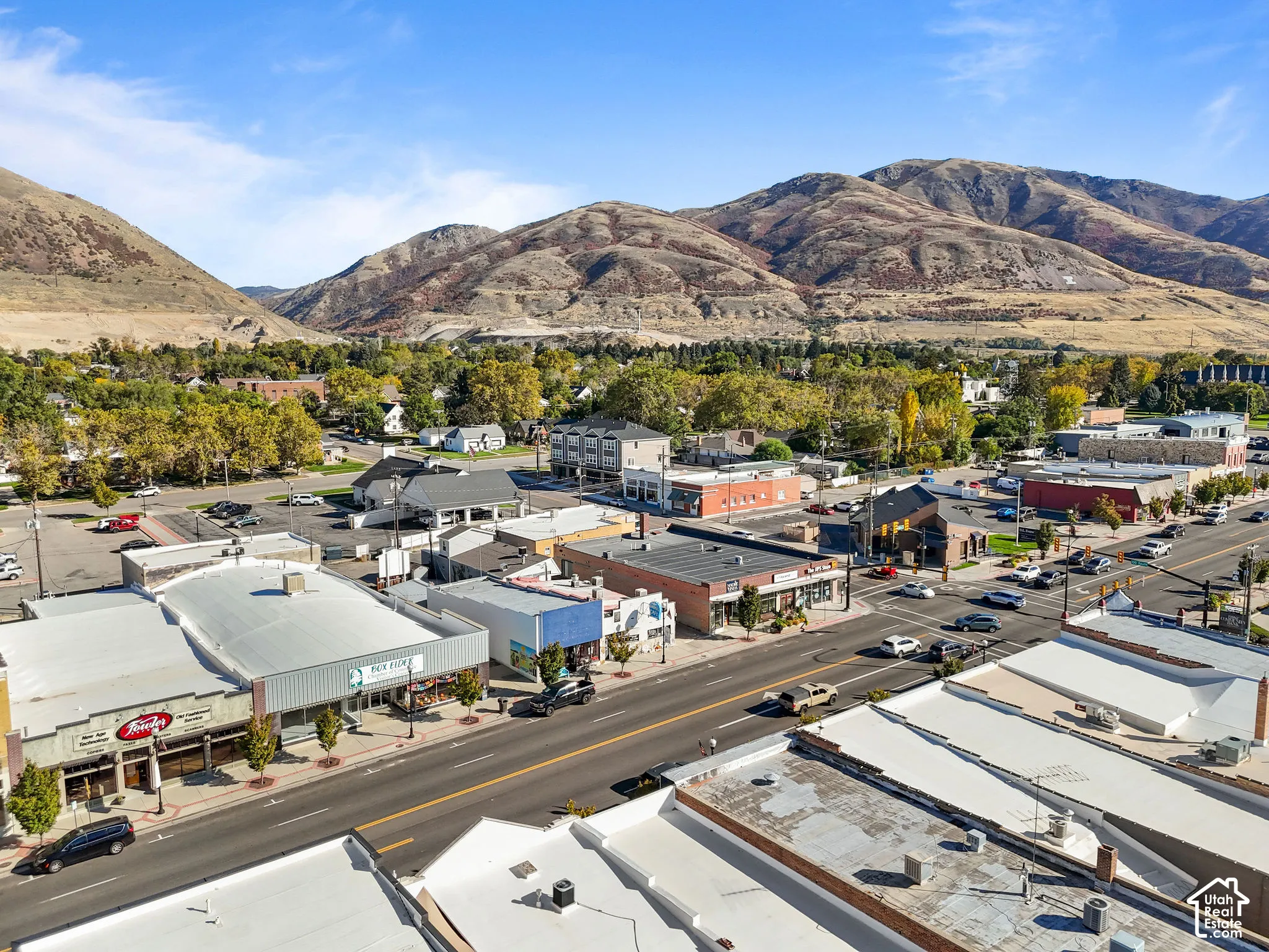 Aerial perspective of a commercial district characterized by varied storefront architecture and prominent mountain range backdrop