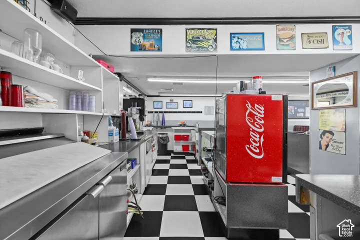 Commercial kitchen space featuring stainless steel cabinetry, integrated shelving, and linear lighting