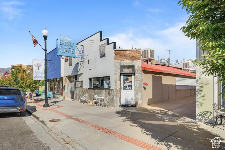 Commercial building exterior featuring a stepped roofline, multi-textured stone masonry facade, metal roofing accents, and a wide street-level entrance and alley