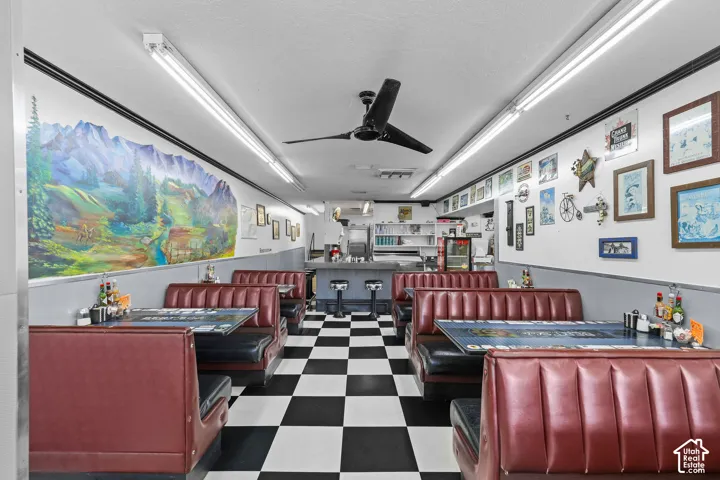 Commercial space featuring  built-in booth seating, integrated service counter, wall-mounted ceiling fan, and fluorescent track lighting