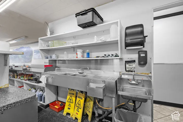 Stainless steel multi-compartment sink, separate hand-washing sink, built-in open shelving, and wall-mounted dispensers
