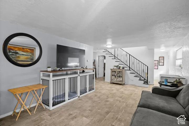 Open-concept interior featuring wood-finish tile flooring, a staircase with matte black metal railings, and textured wall finishes