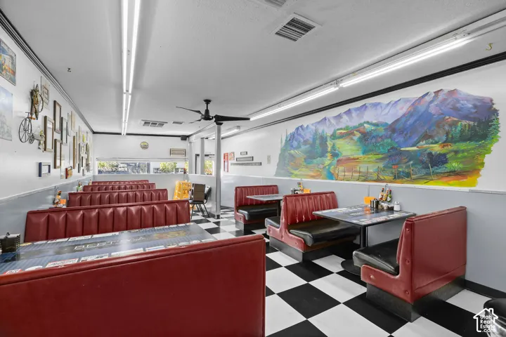 Spacious interior featuring high-contrast checkerboard flooring, integrated booth seating, linear fluorescent lighting, a ceiling-mounted fan, and a large-scale wall mural