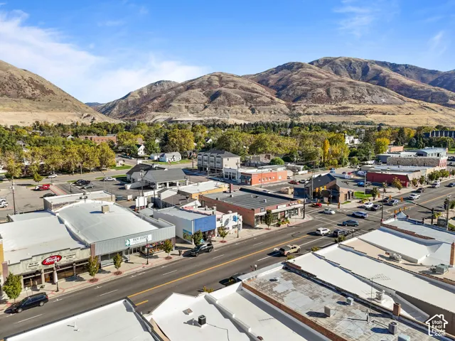 Aerial perspective of a commercial district characterized by varied storefront architecture and prominent mountain range backdrop