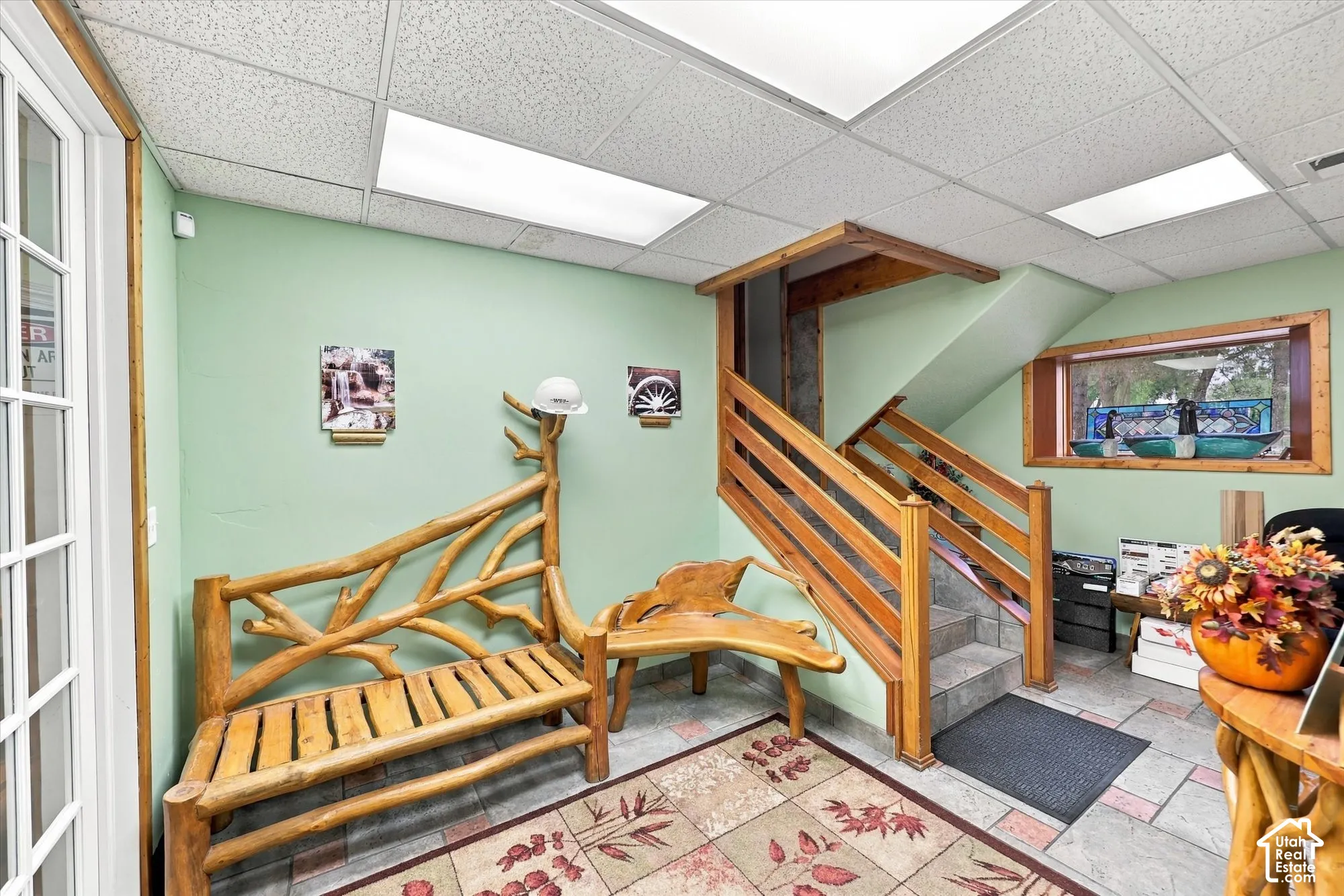 Interior space featuring stone tile flooring, a staircase with wood railings, recessed panel ceiling lights, and wooden window trim