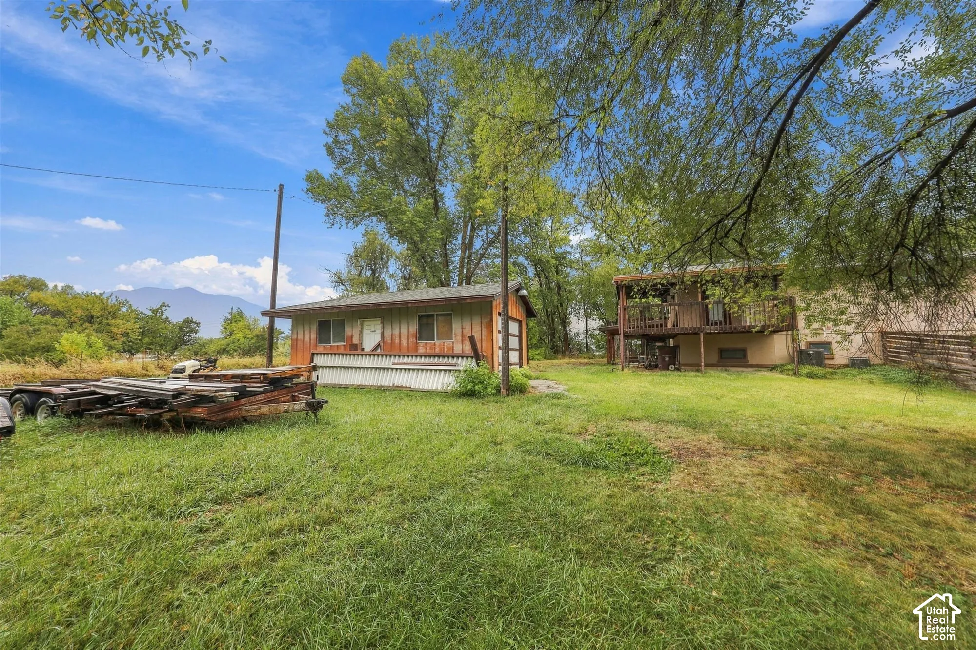 Expansive grounds featuring a detached workshop, mature trees, and mountain scenery