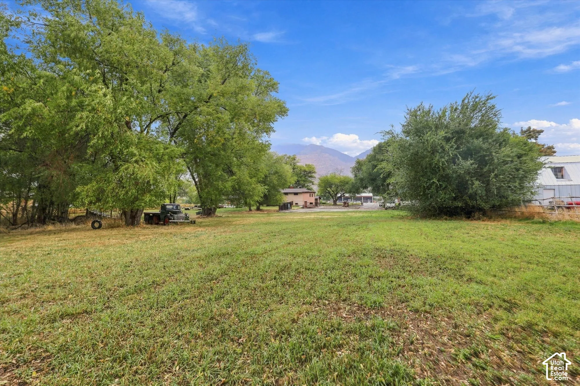Expansive lot featuring mature trees, open green space, and mountain backdrop