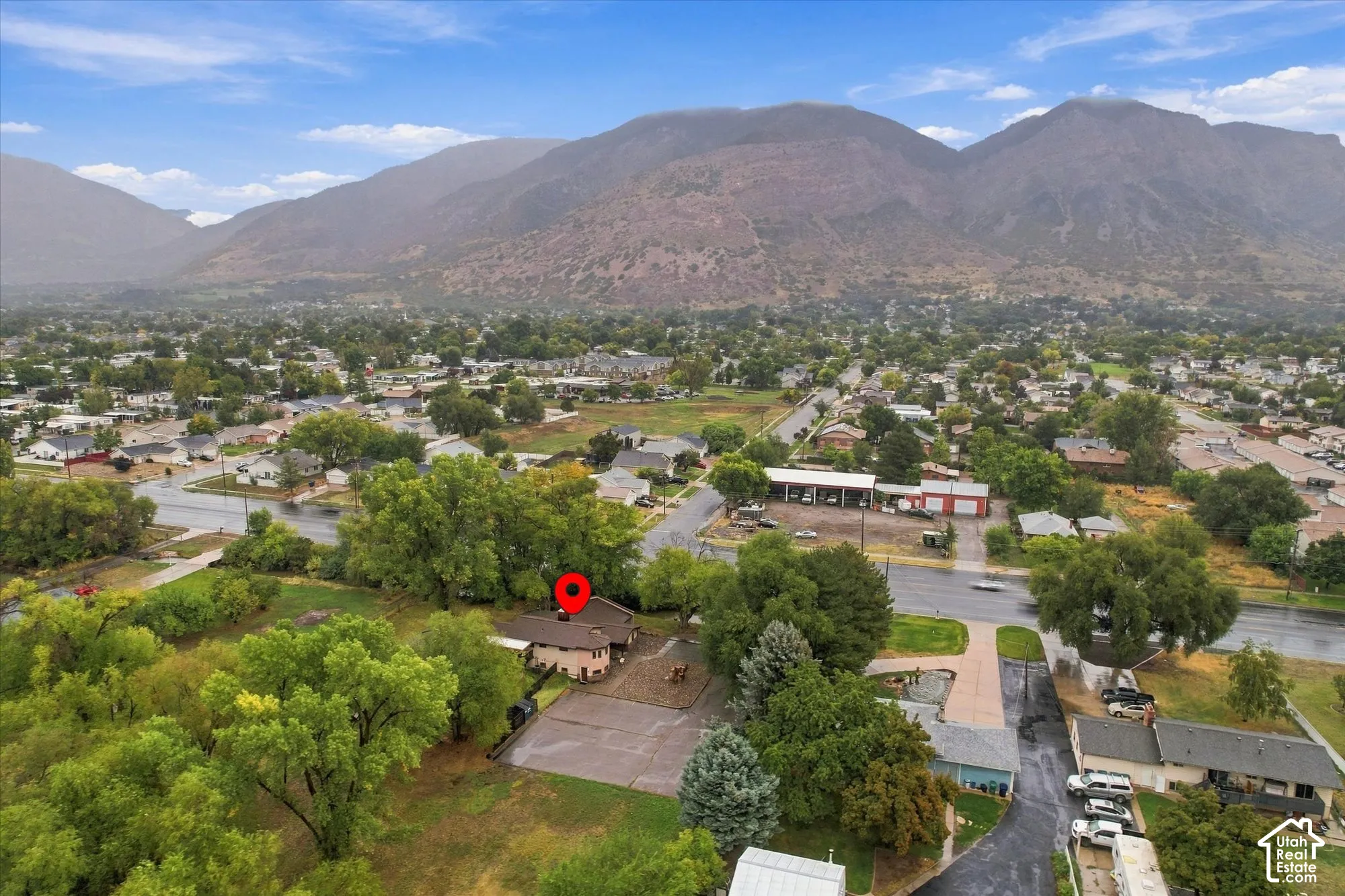 Aerial perspective of a detached residential property situated on a lot featuring mature trees and expansive mountain topography
