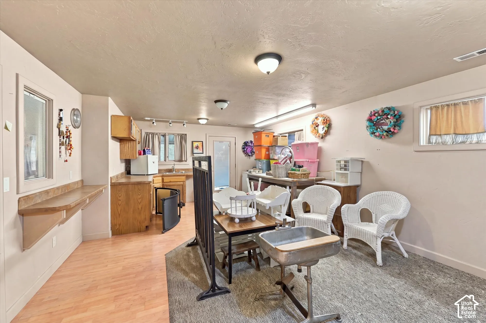 Utility area featuring wood-finish flooring, a built-in laminate countertop workstation, wood cabinetry, a utility sink, and multiple ceiling-mounted light fixtures