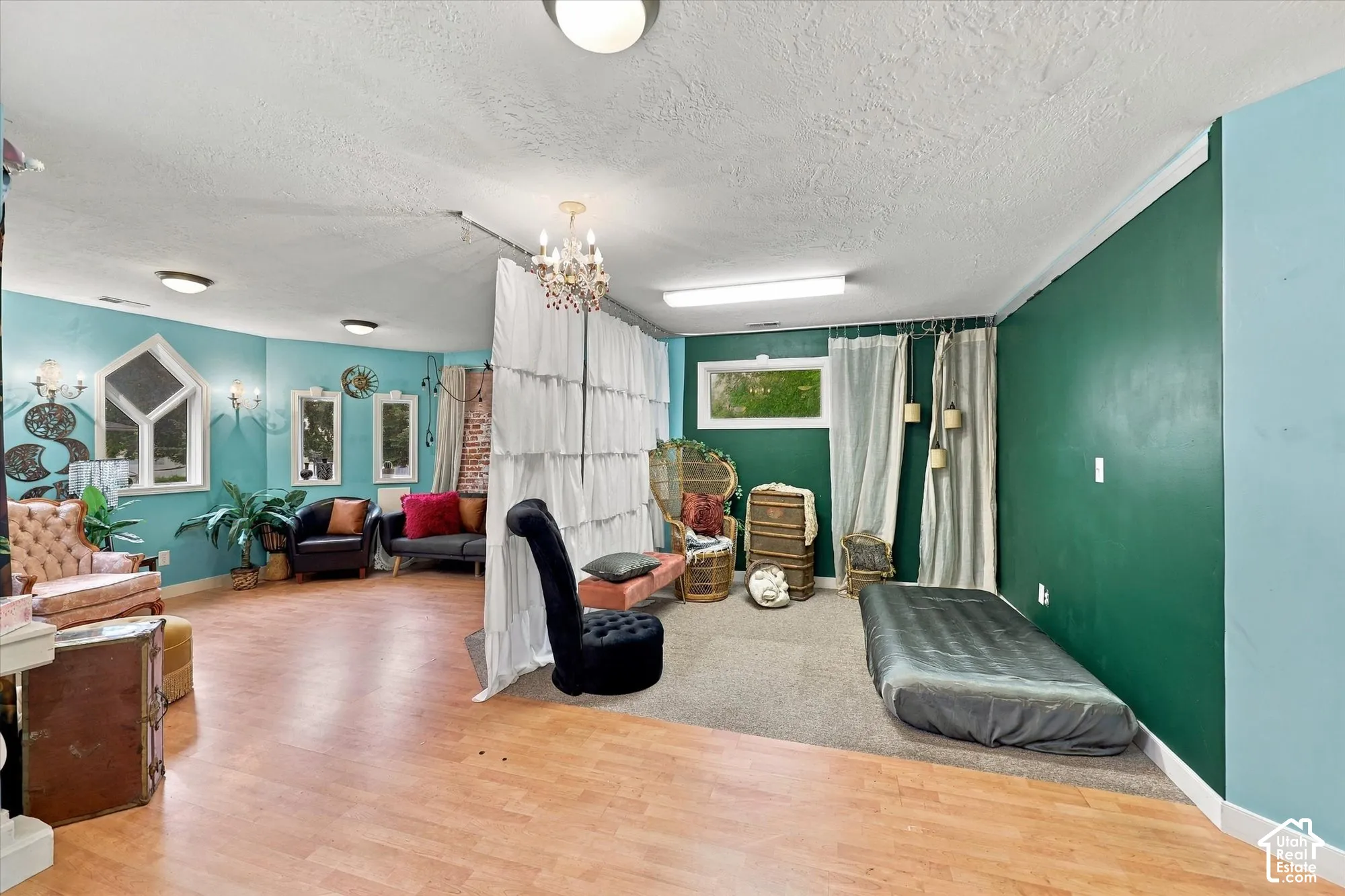 Interior space featuring wood-finish flooring, carpeted area, custom crown molding, decorative chandelier, and exposed brick accents
