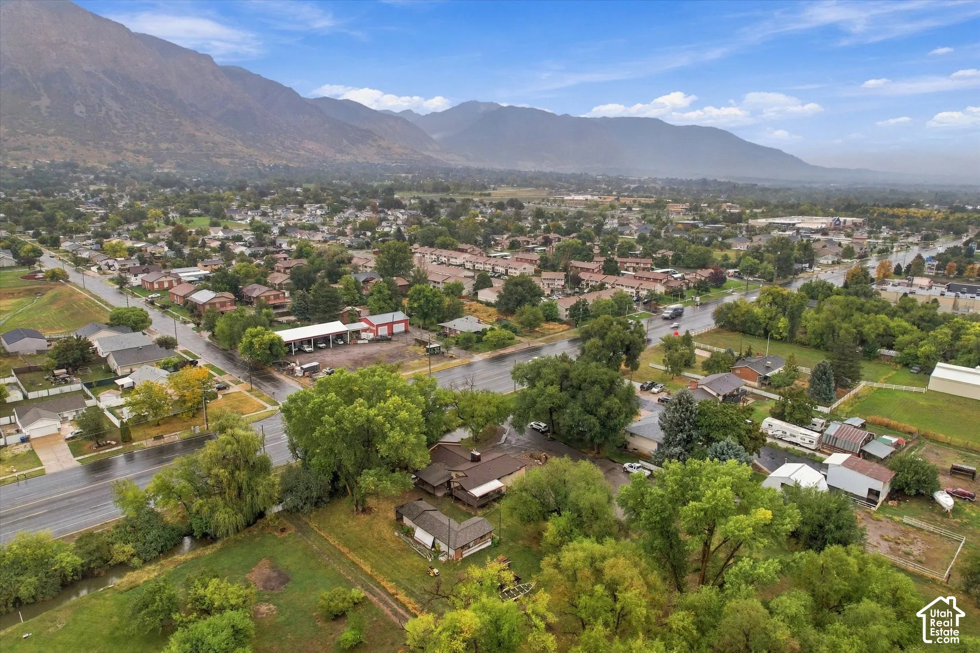 Aerial perspective featuring a residential lot with mature trees and proximity to mountain terrain