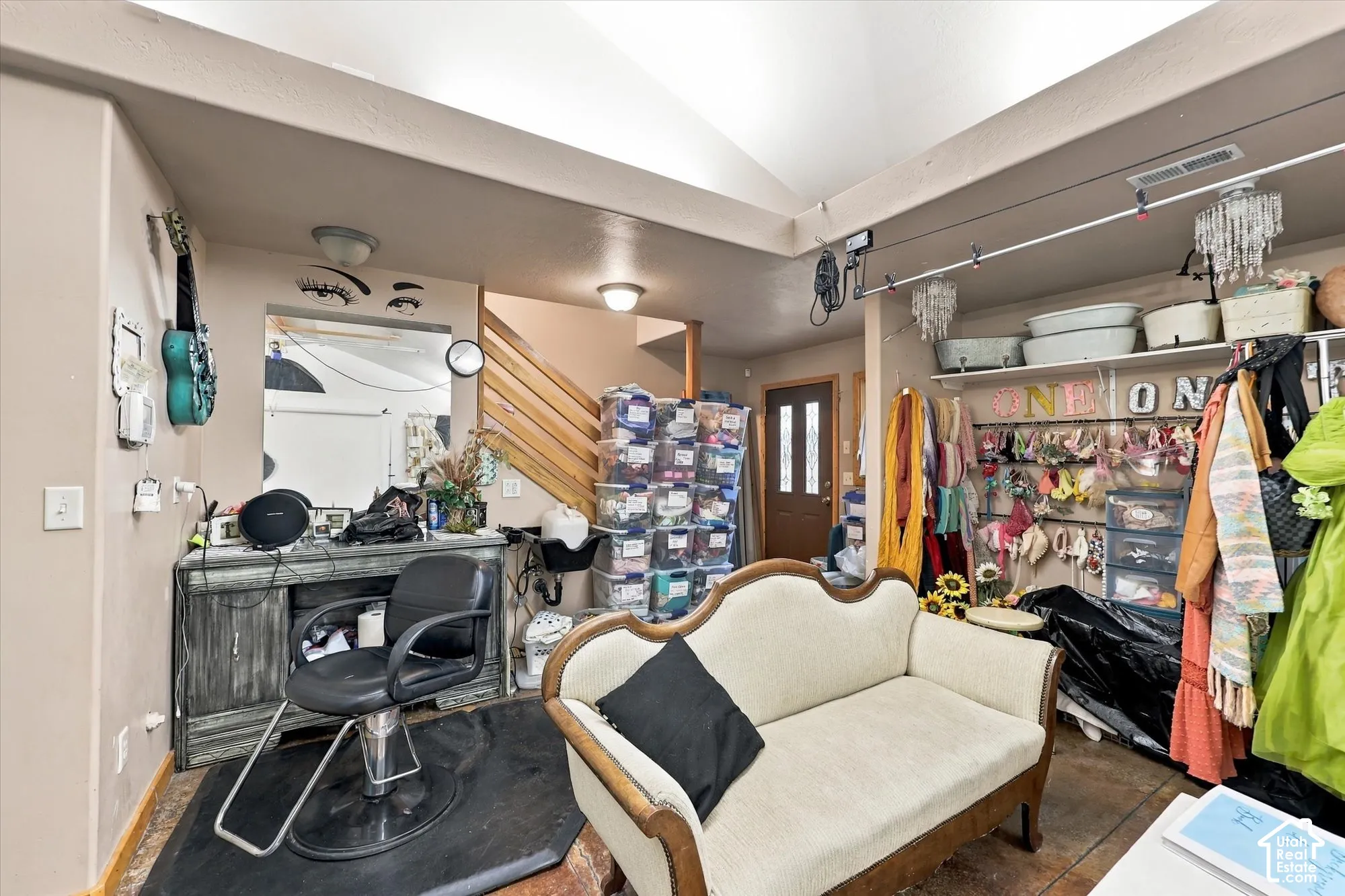 Vaulted ceiling, wall-mounted mirror, wood-slat staircase railing, and exterior entry door