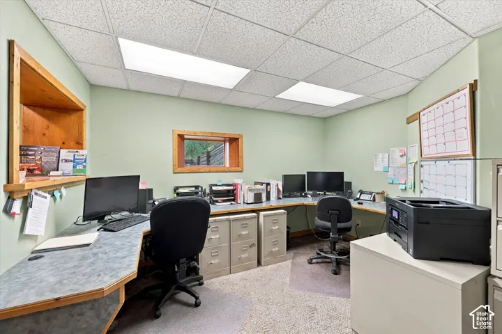 Built-in L-shaped workstation with laminate surface, recessed wood-trim window shelving, and drop ceiling with integrated rectangular lighting