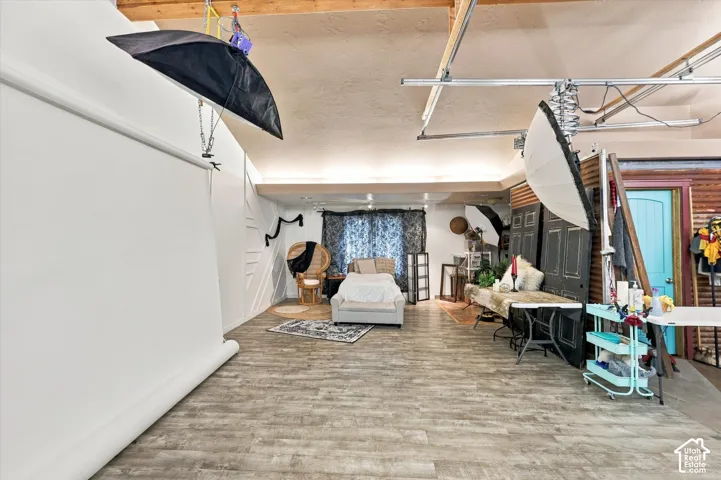 Expansive interior space featuring vaulted ceilings, exposed wooden beams, wood-finish flooring, and decorative wall paneling