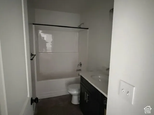 Bathroom featuring a tub and shower combination with white surround, dark-finish cabinetry, countertop with integrated sink, and brushed metal hardware
