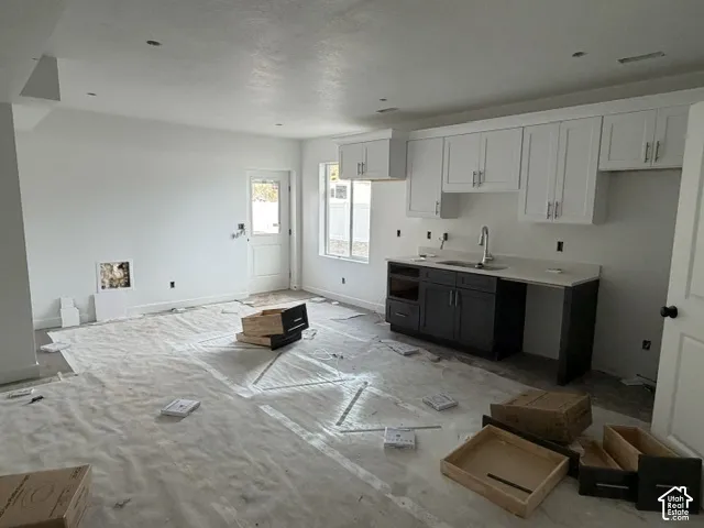 Kitchen featuring two-tone cabinetry, solid surface countertops, recessed lighting, and a dual-basin sink with a high-arch faucet
