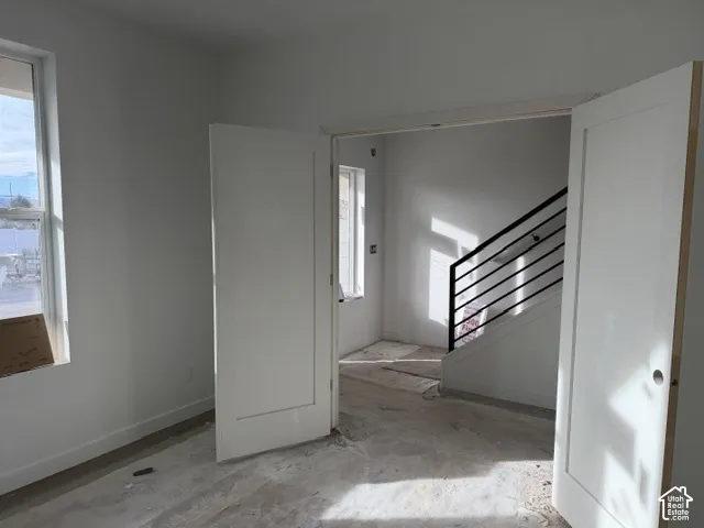 Double doors with shaker-style detailing, tall rectangular windows, and a staircase featuring horizontal black metal railings
