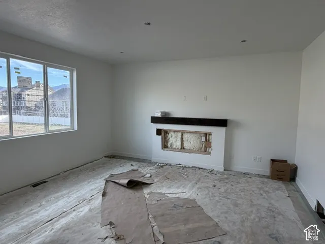 Neutral-toned interior featuring recessed lighting, a large window, and a fireplace surround with a dark wood-finish mantel