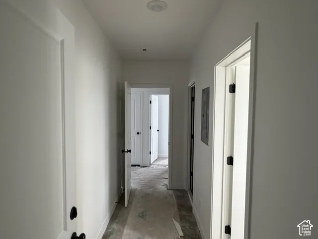 Hallway featuring smooth-finish walls, recessed ceiling lighting, and solid-core doors with matte black hardware