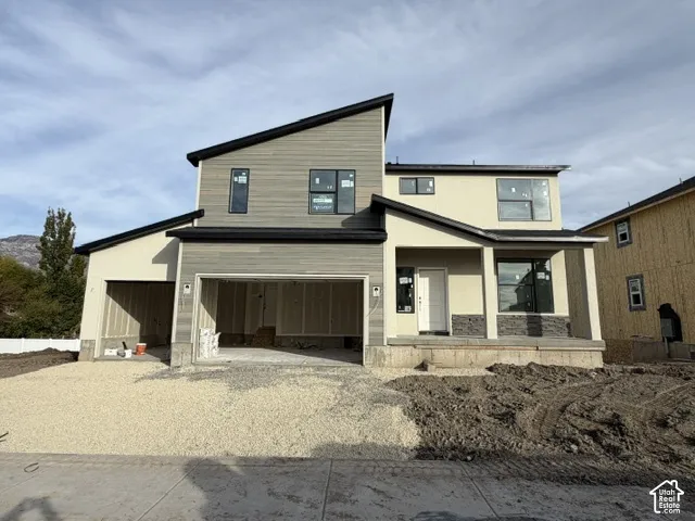 Modern multi-level exterior featuring horizontal siding, stucco finish, stone veneer accents, an asymmetric roofline, and an attached multi-car garage