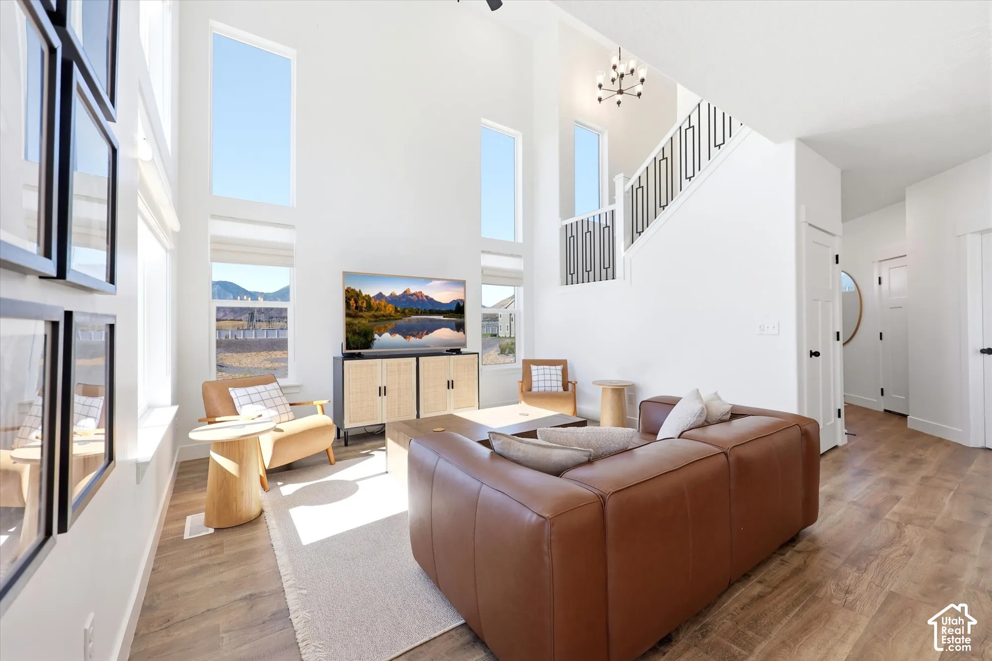 Double-height ceilings, floor-to-ceiling windows, wood-finish flooring, and a staircase featuring metal railings