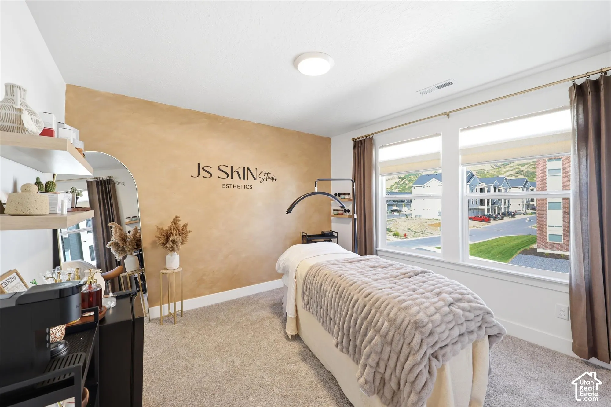 Room featuring a textured accent wall, wall-to-wall carpeting, and double-pane windows with white trim