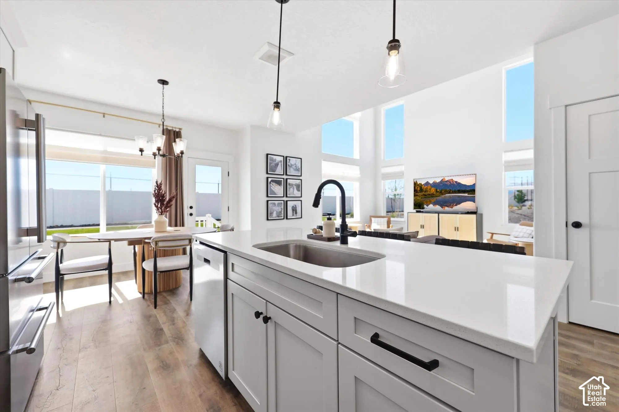 Kitchen featuring a central island with quartz countertops, undermount stainless steel sink, matte black gooseneck faucet, shaker-style cabinetry, and wood-finish flooring