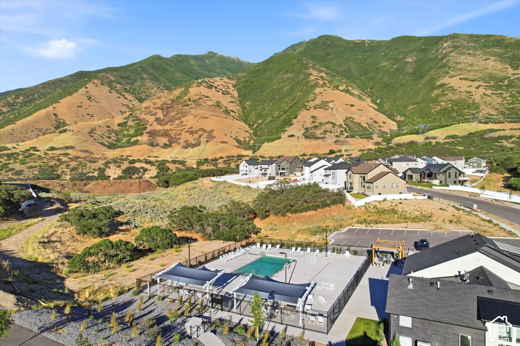 Outdoor swimming pool with integrated sun shades, concrete pool deck, and mountain backdrop
