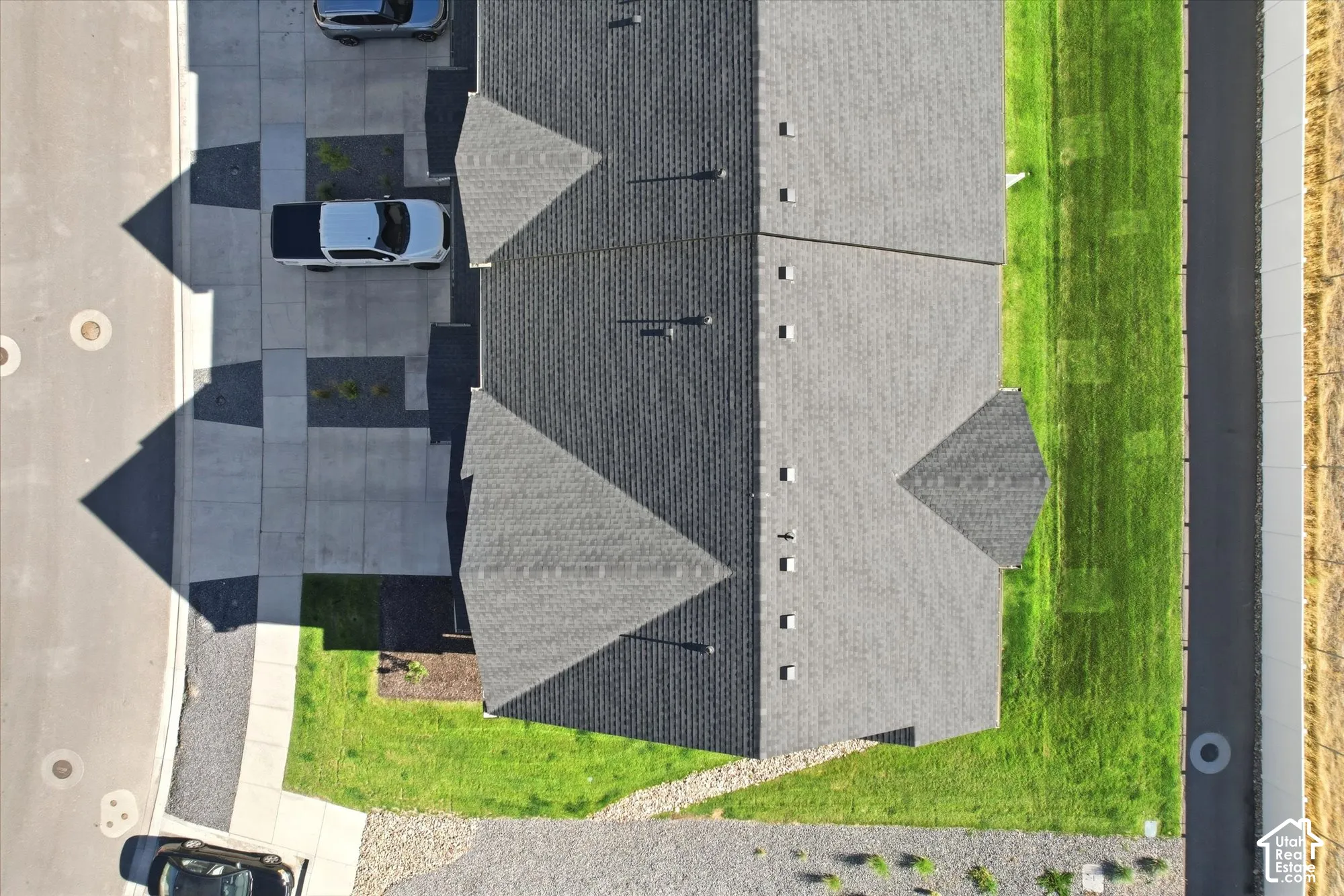 Aerial perspective of a multi-unit property featuring asphalt shingle roofing, concrete driveways, and surrounding manicured lawn areas