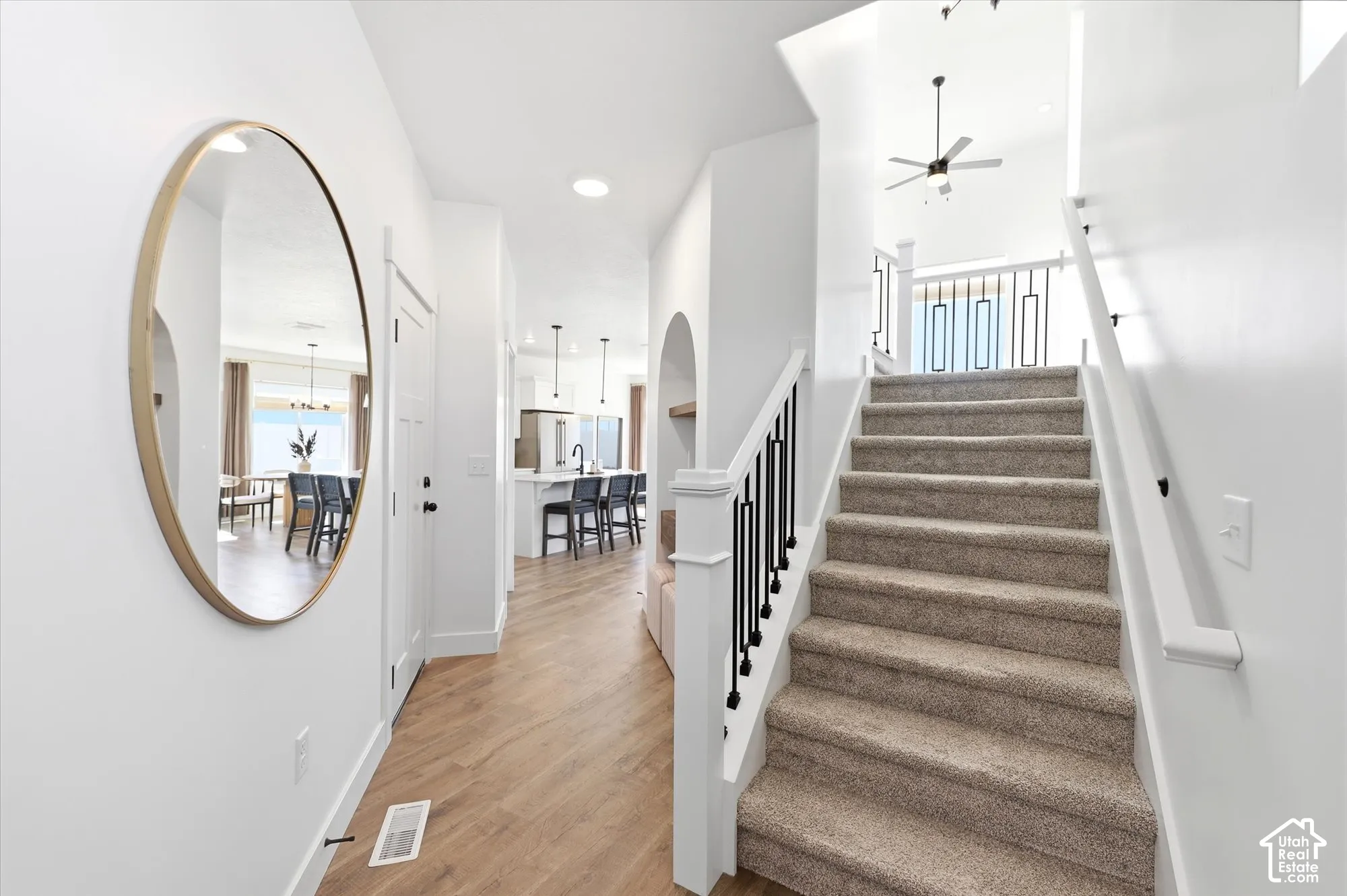 Foyer featuring wood-finish flooring, a staircase with matte black metal balusters and a white handrail, recessed lighting, and an arched built-in alcove