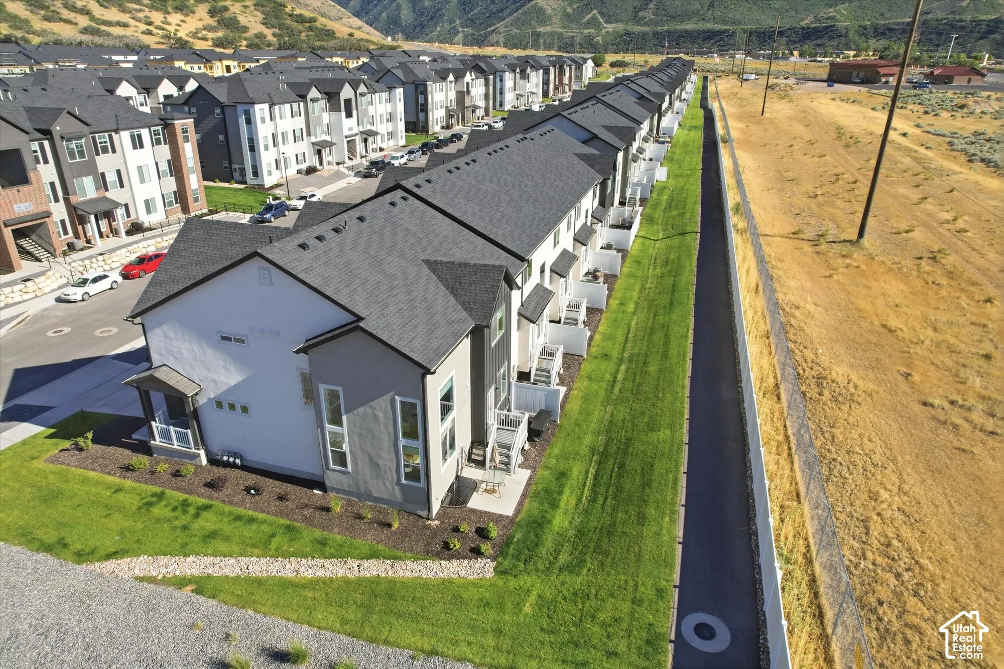 Multi-story townhome featuring a stucco exterior, asphalt shingle roof, concrete patio, and manicured turf borders