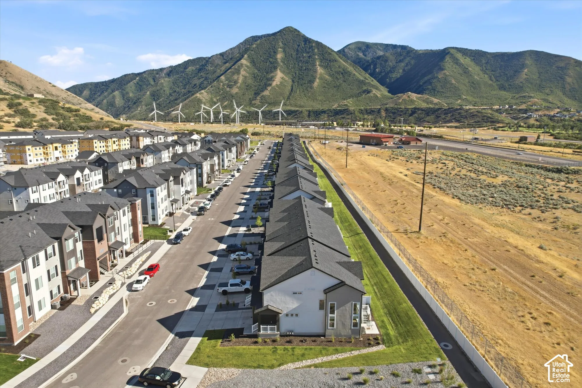 Aerial perspective featuring multi-story residential buildings with shingle roofing and mixed masonry and siding exteriors, set against a backdrop of prominent mountain terrain