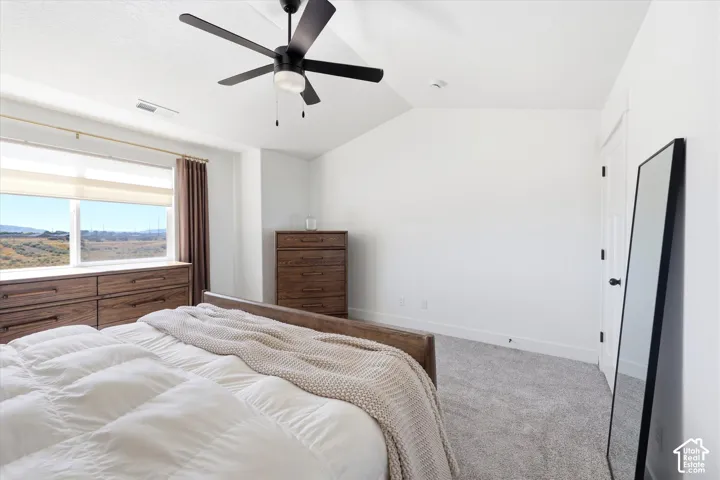 Vaulted ceilings, neutral carpeting, and a matte black ceiling fan with integrated lighting