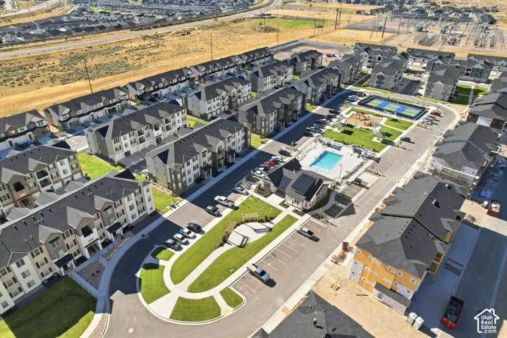 Aerial view of multi-unit residential community featuring a swimming pool, tennis court, playground, and landscaped common areas