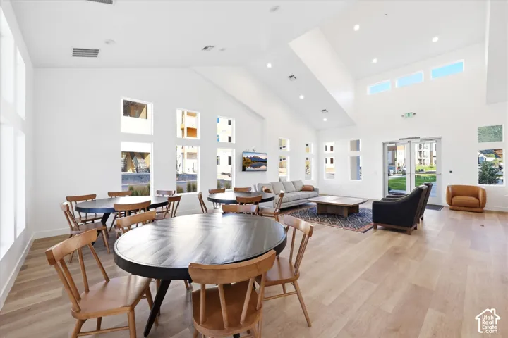Open-concept interior featuring vaulted ceilings, wide-plank wood-finish flooring, abundant natural light from multi-pane windows, and recessed lighting