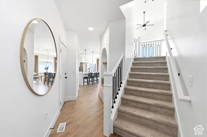Foyer featuring wood-finish flooring, a staircase with matte black metal balusters and a white handrail, recessed lighting, and an arched built-in alcove