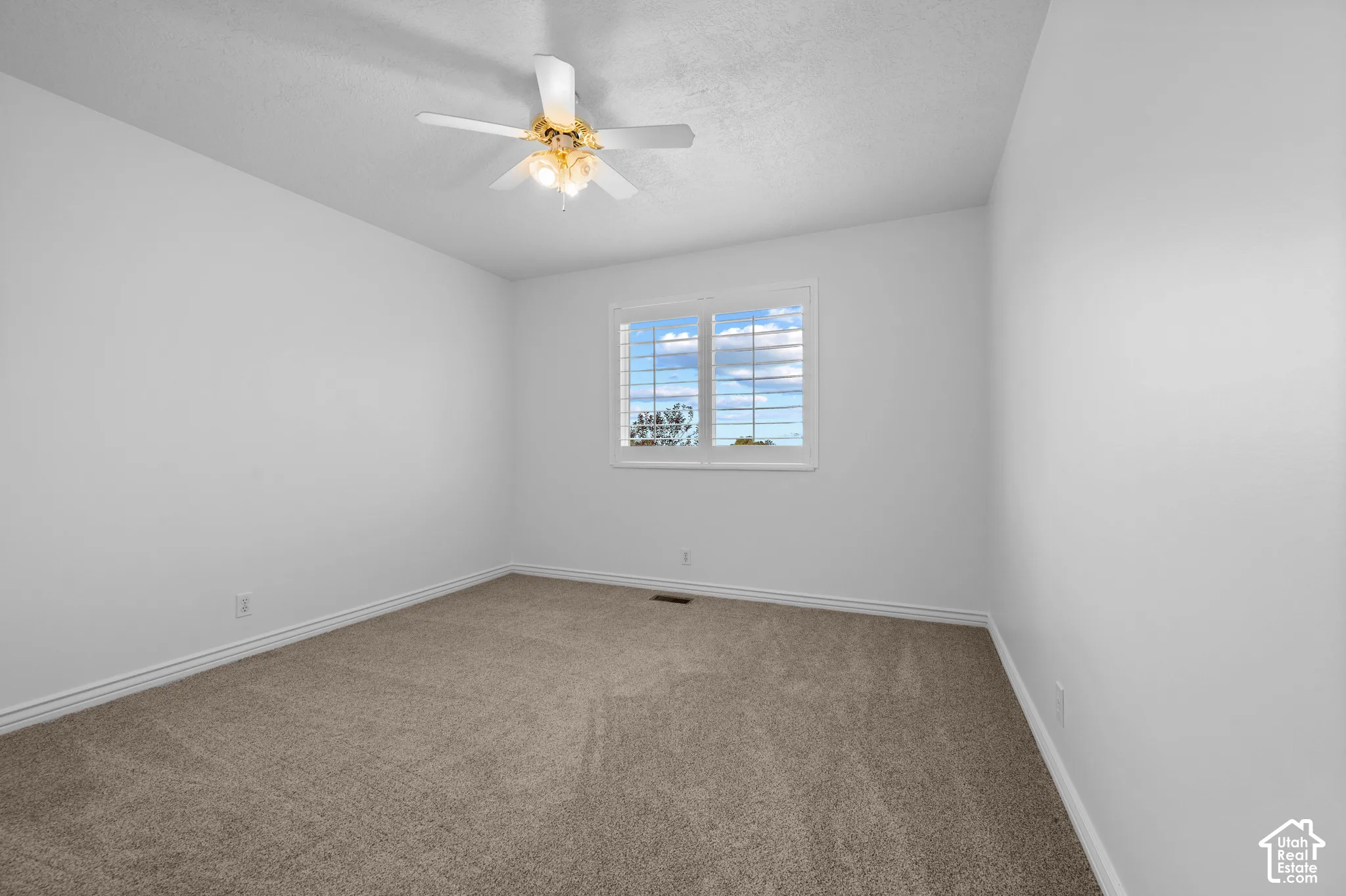 Bedroom with neutral carpeting, a multi-light ceiling fan, and a window with plantation-style shutters