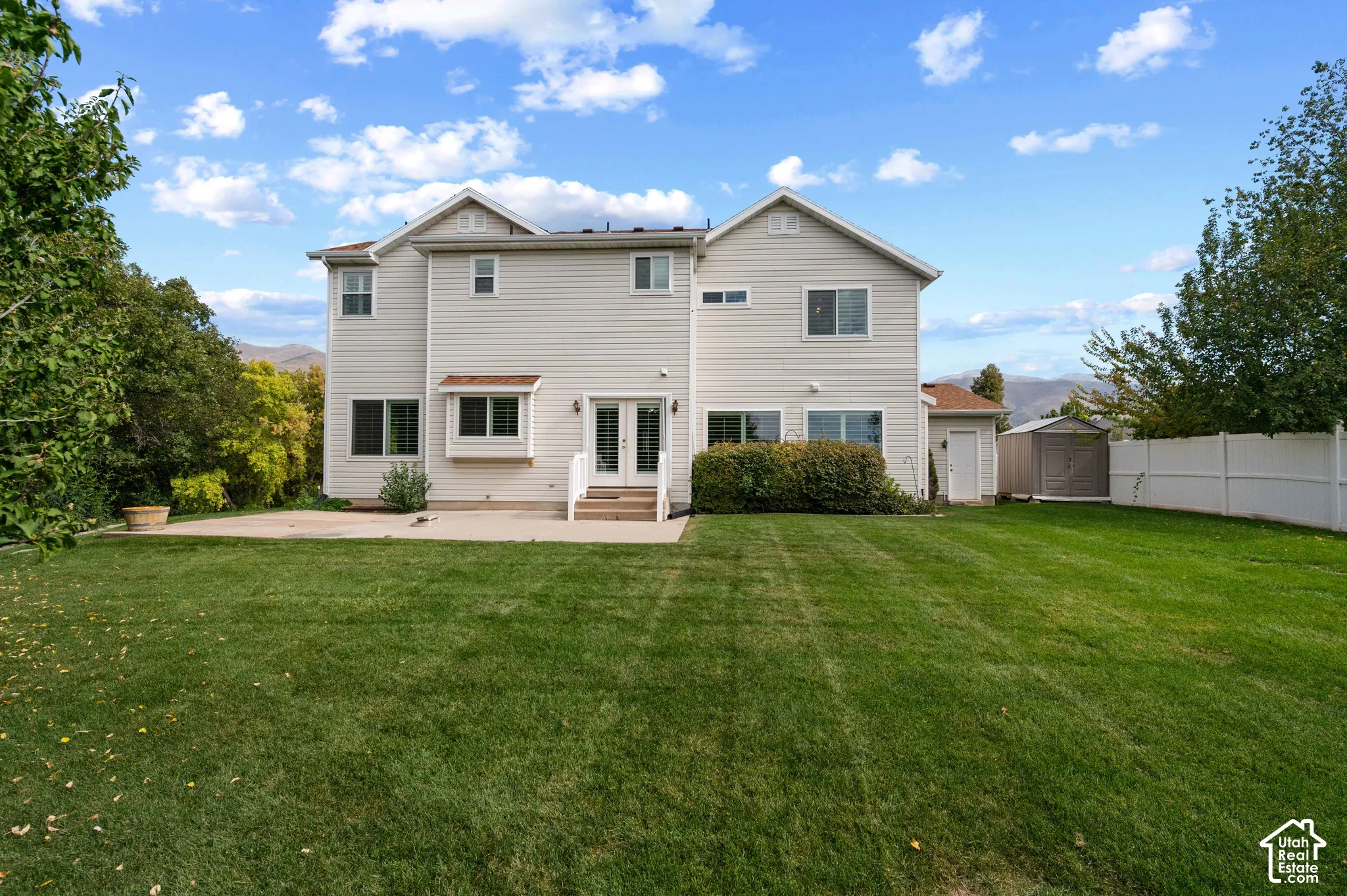 Rear view with light-toned siding, concrete patio, and expansive lawn