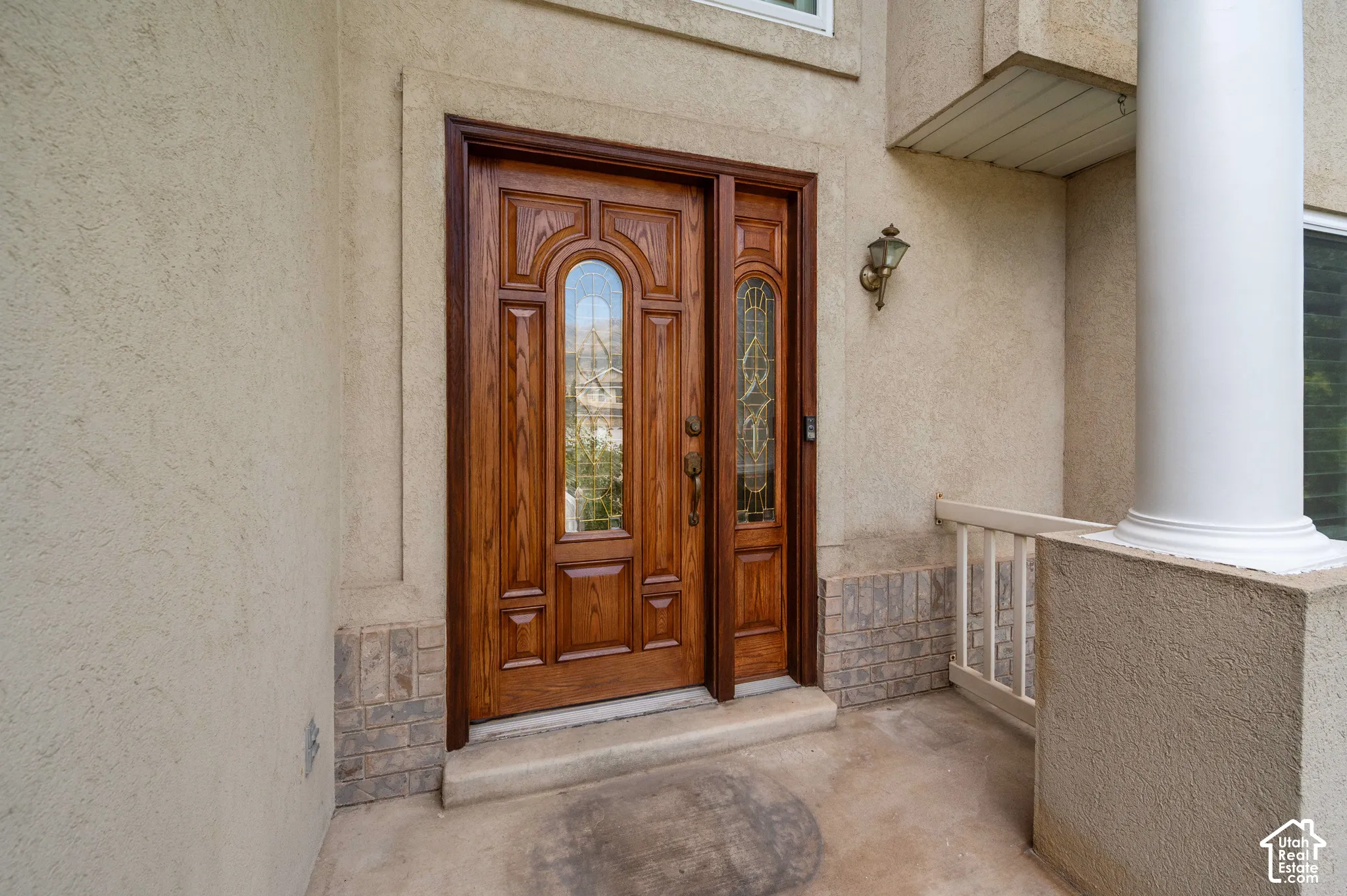 View of wood front door with decorative glass inserts, and a matching side light