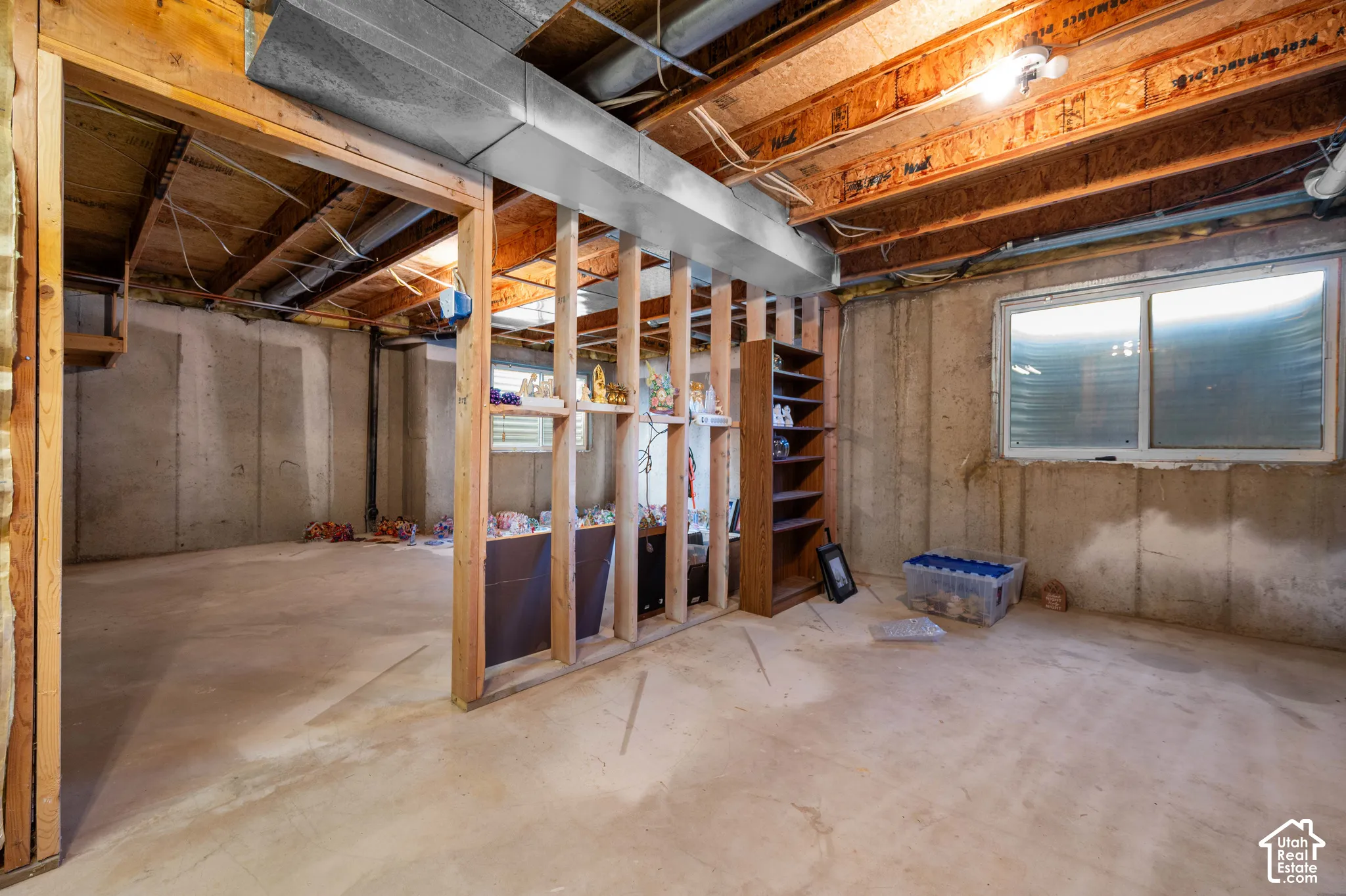 Unfinished basement featuring exposed wood-stud framing, and concrete flooring