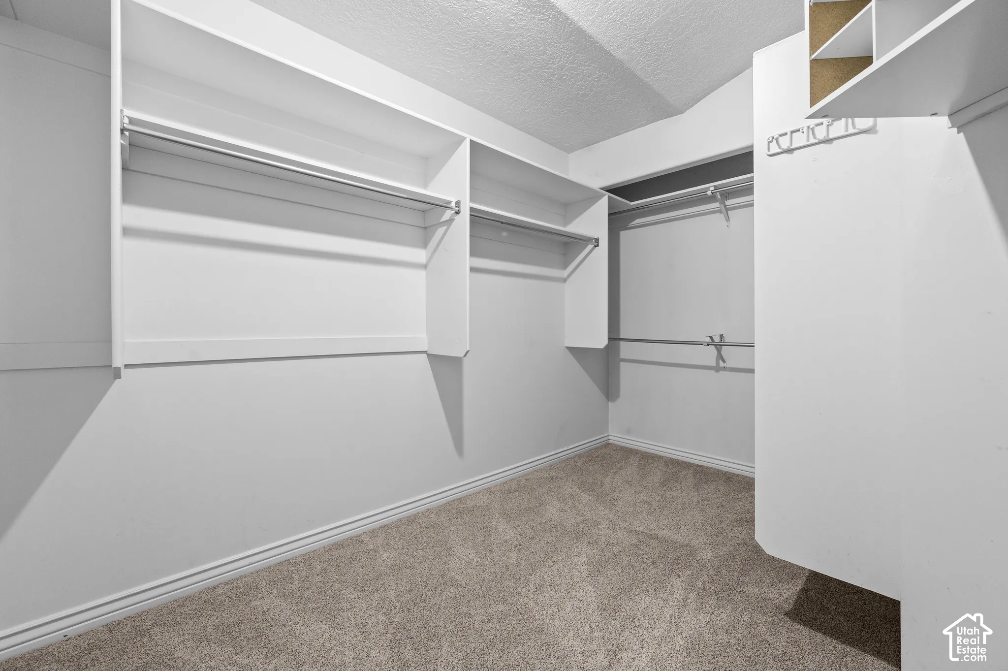 Primary bedroom walk-in closet featuring tiered shelving, built-in hanging rods, and overhead storage compartments