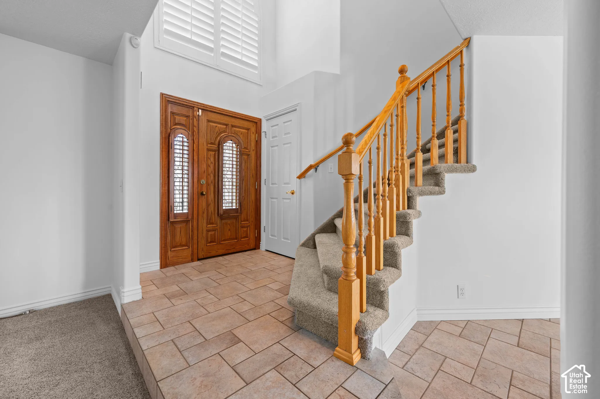 Entryway featuring tile flooring, and staircase with wooden railings