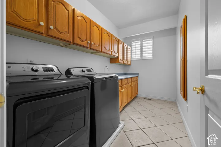 Laundry room with tile flooring, a sink, and plantation-style window shutters