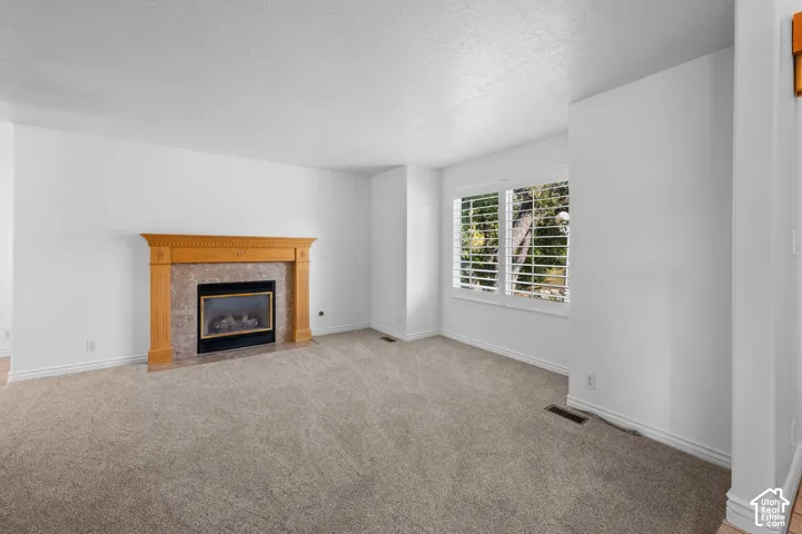 Living room featuring a fireplace with a decorative wood mantel, accompanied by interior plantation shutters