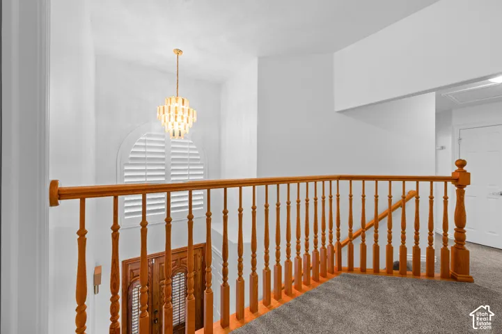 Upstairs landing area featuring wood spindle railings, a multi-tier pendant chandelier, and a prominent arched window with shutters