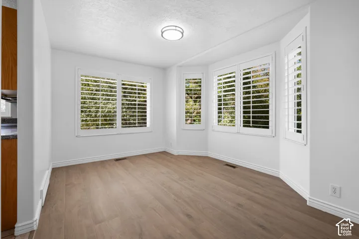 Dining room featuring LVP flooring, a bay window configuration, and white plantation shutters